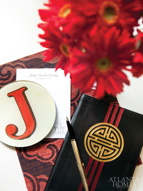 A “J” plate from John Derian & Co. and Bentley’s notebook, pen and notepads with name and pagoda symbol designed by Alston Wise rest on a Schumacher wallpaper.