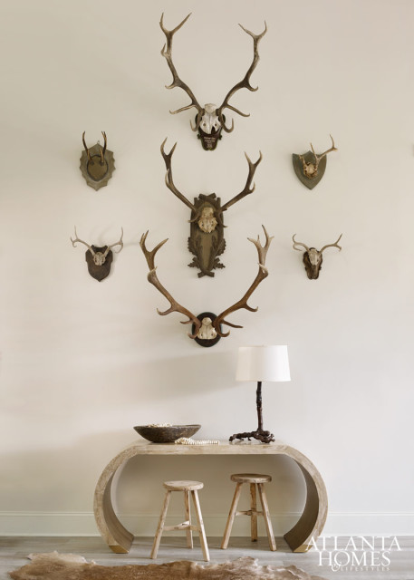 Small and large wall-mounted horns mingle to create one cohesive statement in the foyer. Console, Mrs. Howard. Stools, South of Market. Root lamp, mounted horns and beads, A. Tyner Antiques. Hide rug, Bungalow Classic.