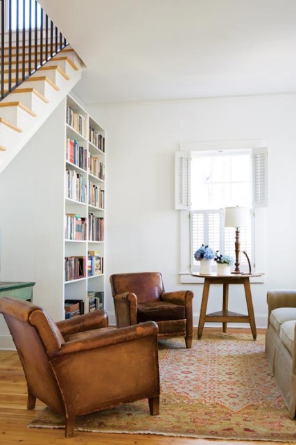 In the family room, built-in storage keeps clutter to an absolute minimum. Bookshelves were built where an awkward wall of doors had once been, and a triangular cabinet under the stairwell allows the children’s toys to be stowed away easily. Leather club chairs, Scott Antique Market. The cricket table belonged to Andrew’s parents.