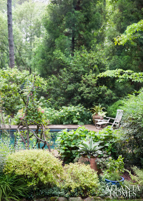 The master bedroom overlooks an idyllic backdrop that includes a pool as well as cultivated mix of climbing and potted plants.