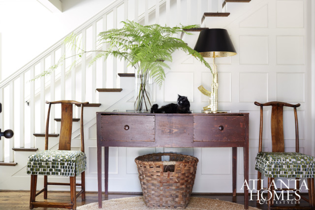 Resident feline Frankie sprawls across the Madison, Georgia, huntboard next to a Philippe Starck AK-47 gold lamp by Flos. Antique Mandarin chairs flank the vignette while a Southern cotton basket fills the space below.
