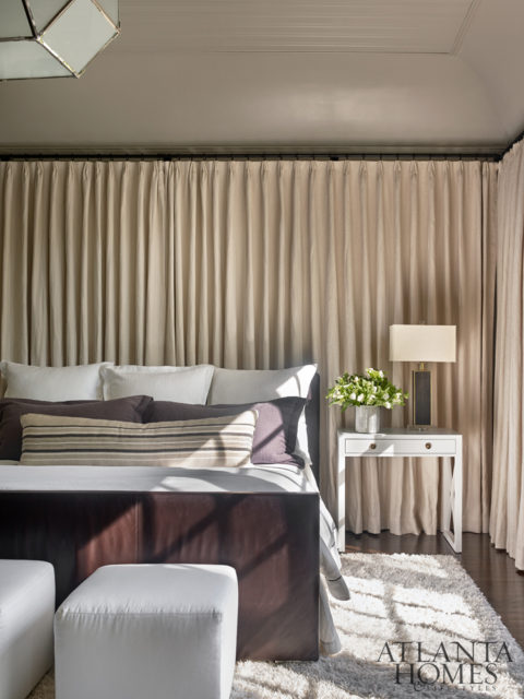 In the master bedroom, a curtained wall adds softness.Webb dressed up the existing bed with bedding from Peacock Alley and custom pillows.