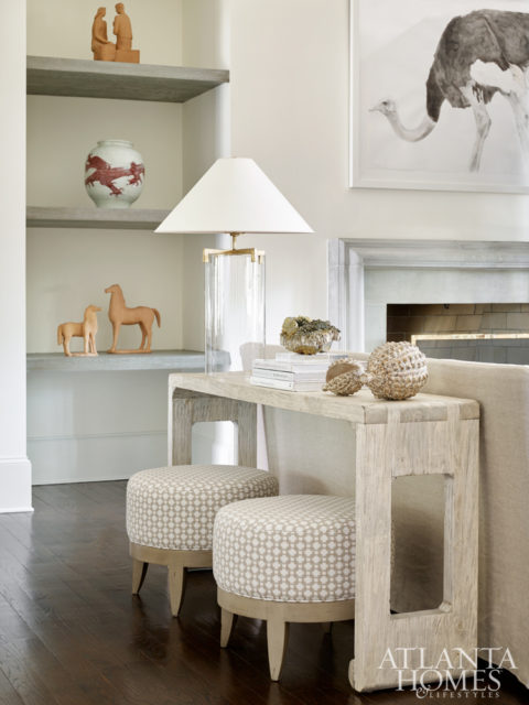 Ottomans covered in a Celerie Kemble for Schumacher fabric rest below a cut-out console.