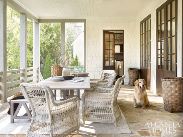 Elegant as any interior space, the porch is a study in natural materials and organic hues, creating a soft and serene scheme. A long, weathered teak table from Janus et Cie anchors the room. It is surrounded by comfortable woven armchairs by Kingsley-Bate. A teak dining bench, also by Janus et Cie, provides plenty of seating for friends and family. The rug is by Dash & Albert. The wicker demijohn is from A. Tyner Antiques.