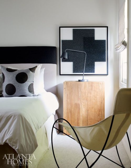 The custom headboard and linens by Kay Douglass Interiors capitalize on the monochromatic tone of the son’s bedroom, where a framed gray cross adds a graphic punch.