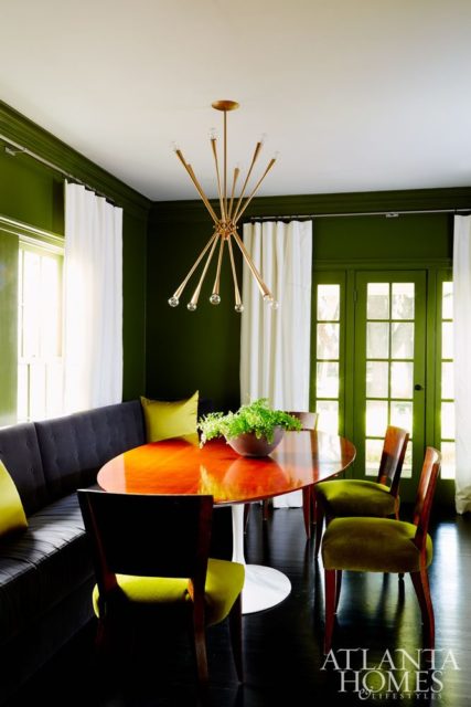 Dramatic walls (painted Avocado by Benjamin Moore), a streamlined banquette and velvet upholstered vintage chairs add an enveloping feel to the otherwise formal dining space.