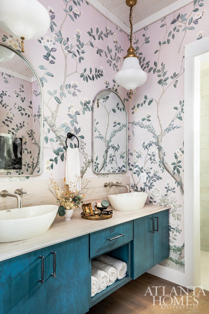 floral pink wallpaper in bathroom with double vanity and blue cabinets