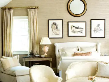 Bedroom with a white sleigh bed, upholstered chairs, and a chaise lounge. Walls are covered in textured beige wallpaper.