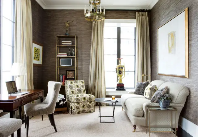 Office with dark textured wallpaper, a wooden desk with a laptop, a patterned armchair, a cream sofa, and a large abstract painting on the wall.
