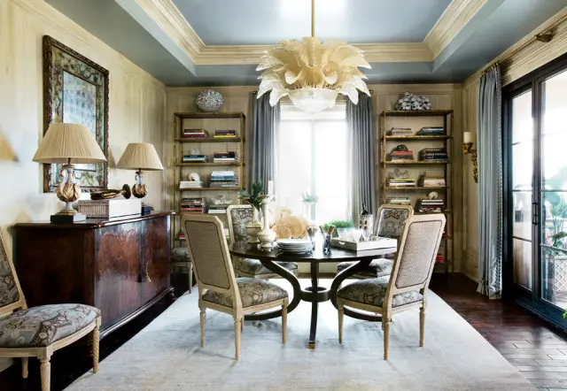 Dining room with a dark wood table and chairs upholstered in patterned fabric, a burl wood buffet, and a large glass chandelier.