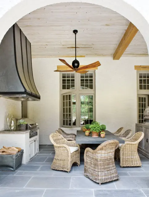 Covered patio with a large dining table and wicker chairs, an outdoor grill, and a ceiling fan.