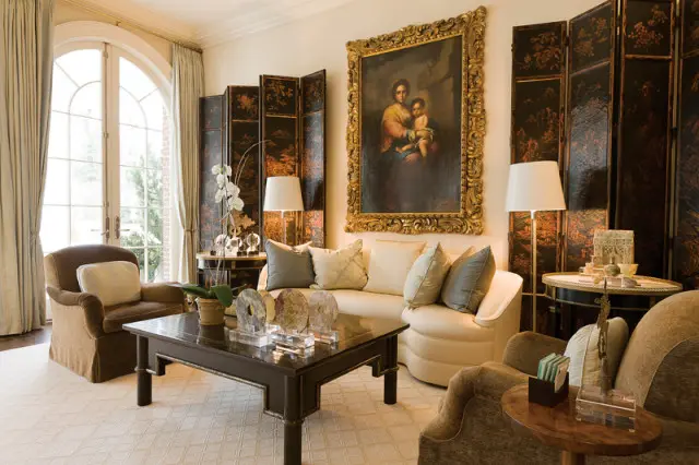 Living room with a cream sectional sofa, dark wood coffee table, ornate gold-framed painting, and folding screens.