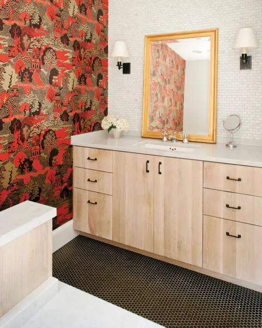 Master bathroom with bold red and gold Chinoiserie wallpaper, light wood vanity with black hardware, white marble countertop, and white subway tile backsplash.