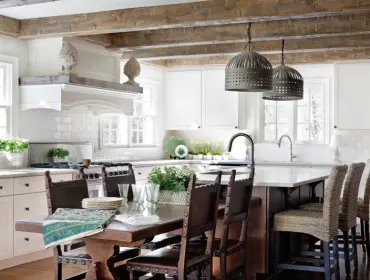 Farmhouse kitchen with white subway tile backsplash, wood beam ceiling, and a dark wood dining table with leather chairs.