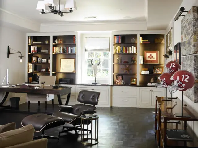Dark wood desk with computer and chair, leather lounge chair with ottoman, and built-in bookshelves filled with books and decor in a home office.