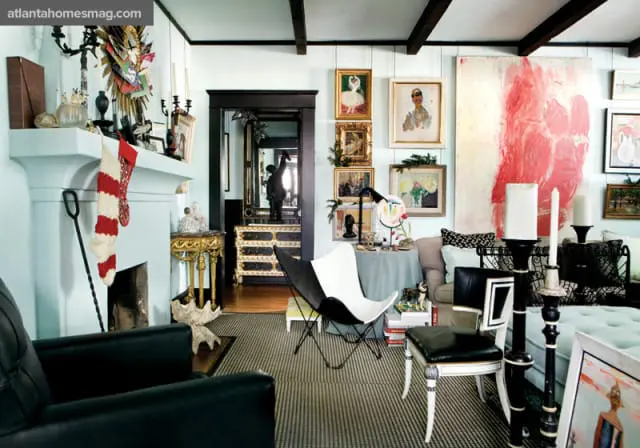Light blue living room with a white fireplace, black leather armchairs, a black and white butterfly chair, and numerous pieces of art on the walls.