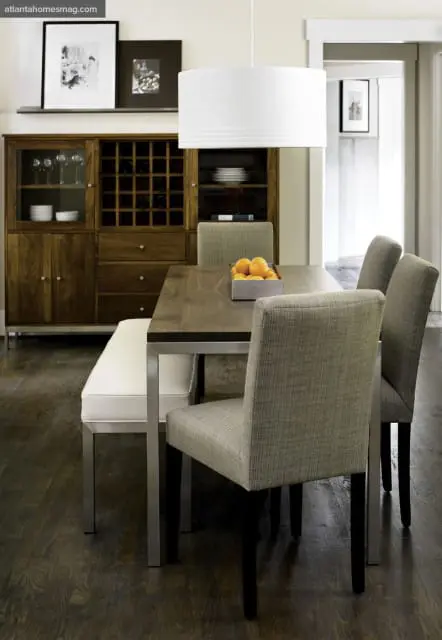 Dining room with dark wood floors, a dark wood buffet with glass doors and wine rack, and a dark wood dining table with upholstered chairs and a bench.