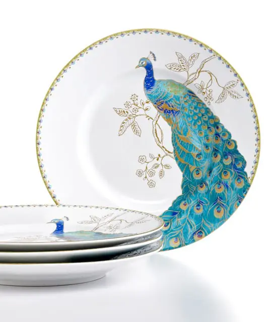 White porcelain plates with gold trim and detailed peacock illustrations in blue, green, and gold