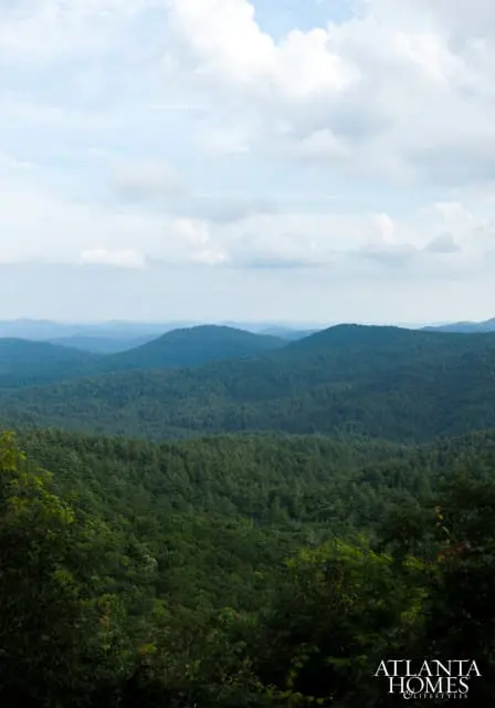 Rolling green mountains covered in dense forest under a cloudy sky. The Atlanta Homes & Lifestyles logo is in the bottom right corner.