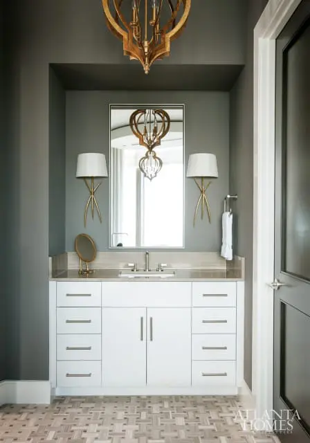 Powder room with gray walls, white vanity with marble countertop, gold chandelier, and geometric tile flooring.