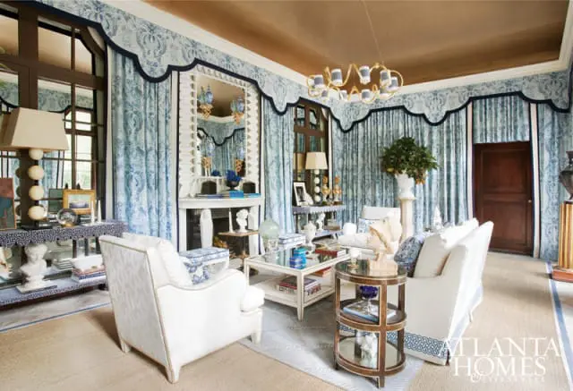 Living room with blue toile wallpaper, white upholstered furniture, a white fireplace, and a gold chandelier.