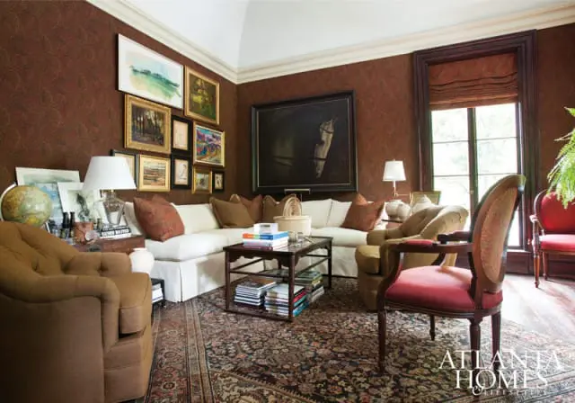 Living room with dark patterned wallpaper, white sectional sofa, antique rug, gallery wall of paintings, and a large horse portrait above the sofa.