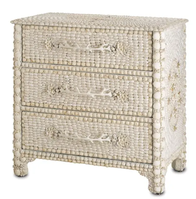 Three-drawer chest covered in small white seashells with coral branch drawer pulls and shell embellishments.
