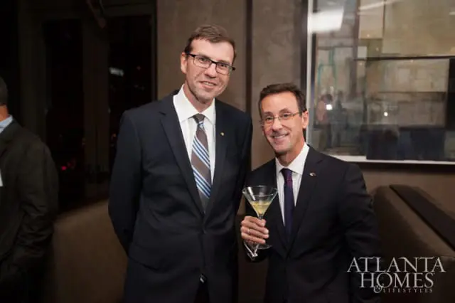 Two men in suits at an event. The man on the right holds a martini glass. The Atlanta Homes & Lifestyles logo is in the bottom right corner.
