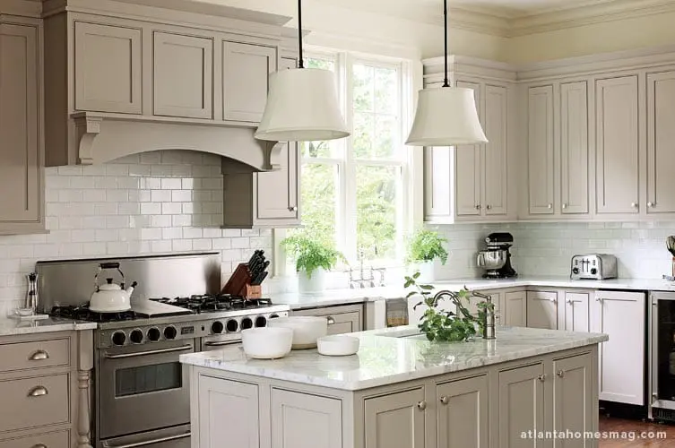 Gray kitchen with white subway tile backsplash, marble island, stainless steel range, and white pendant lights.