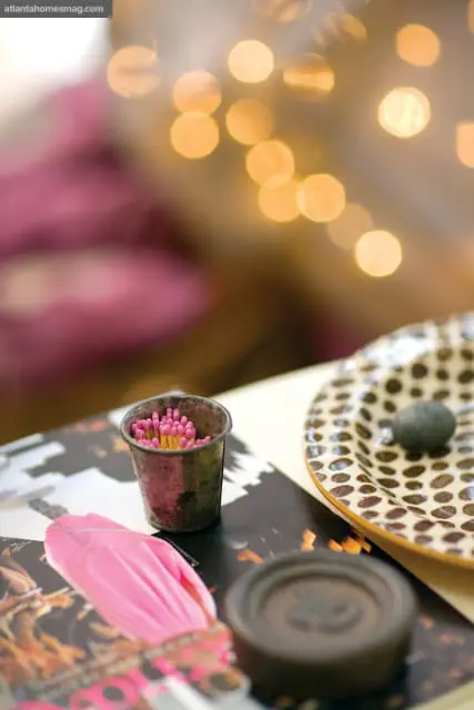 Close-up of pink-tipped matches in a distressed metal cup on top of a magazine with a pink floral design.