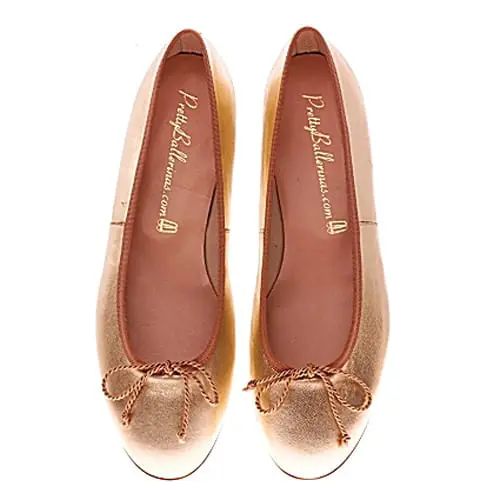 Pair of rose gold ballet flats with a bow detail on the toe and "Pretty Ballerinas.com" printed on the insole.