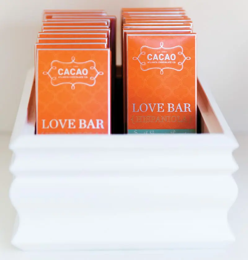 Orange chocolate bar wrappers with silver text that reads "CACAO" and "LOVE BAR" in a white decorative box.