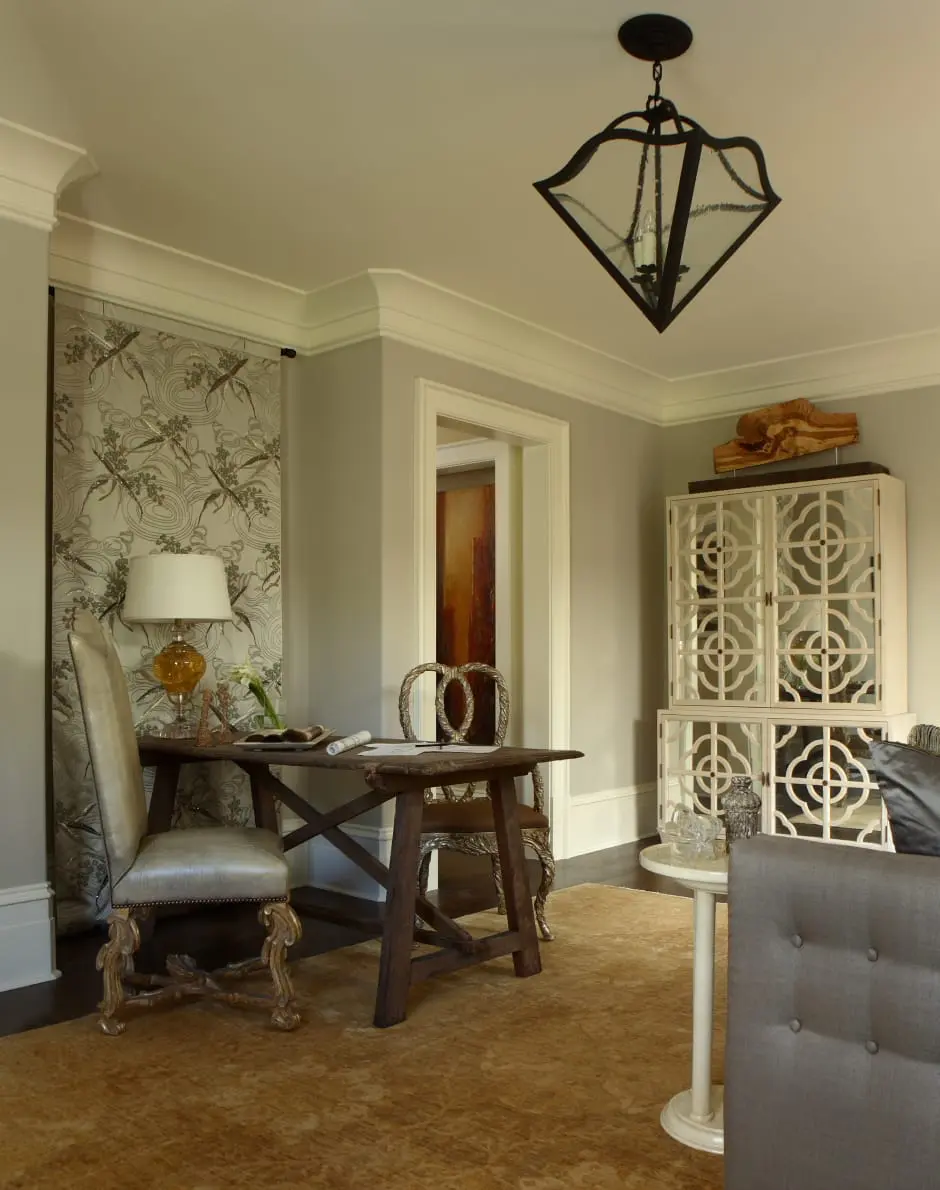 Study with a dark wood desk and ornate chairs, a patterned tapestry, a white cabinet with decorative doors, and a large textured rug.