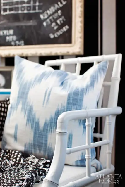 White bamboo-style chair with blue and white ikat pillow and black and white patterned throw
