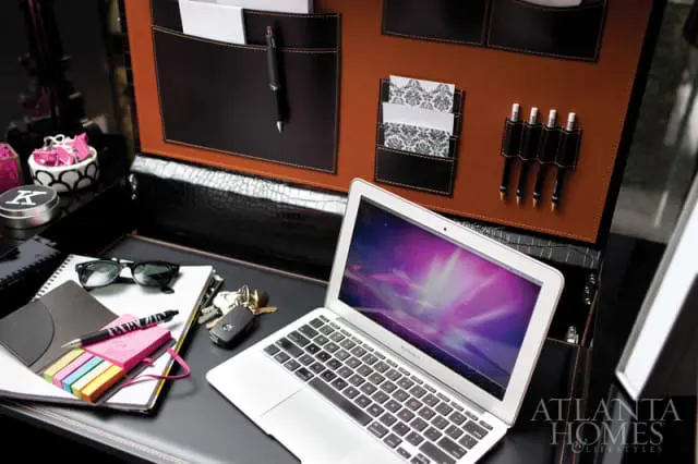 Desk with a laptop, notebook, sunglasses, keys, and a leather organizer with pockets for pens and cards.