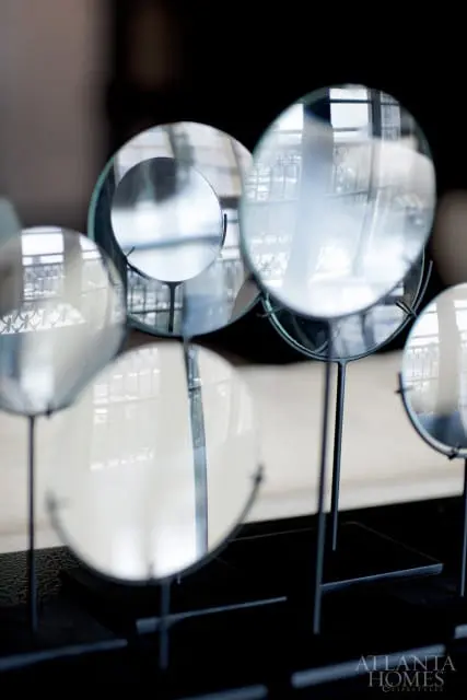 Collection of round mirrors on black stands, reflecting a window with an ornate balcony