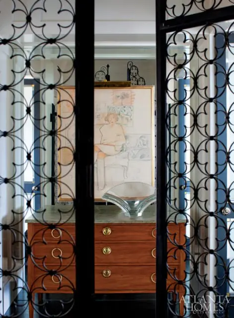 Wooden dresser with brass hardware and a green marble top, topped with a glass sculpture and framed artwork.