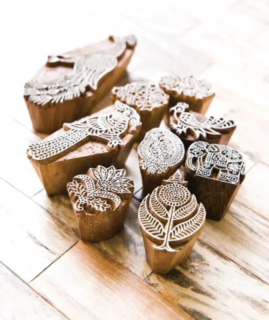 Collection of wooden hand-carved printing blocks with intricate floral and animal designs, including peacocks and elephants.