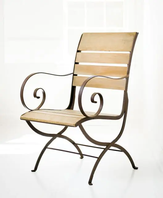 Ornate dark metal armchair with curved arms and legs, featuring slatted light wood seat and back