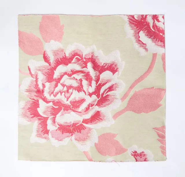 Close-up of a pale green fabric with a large, textured floral pattern in shades of pink and white.