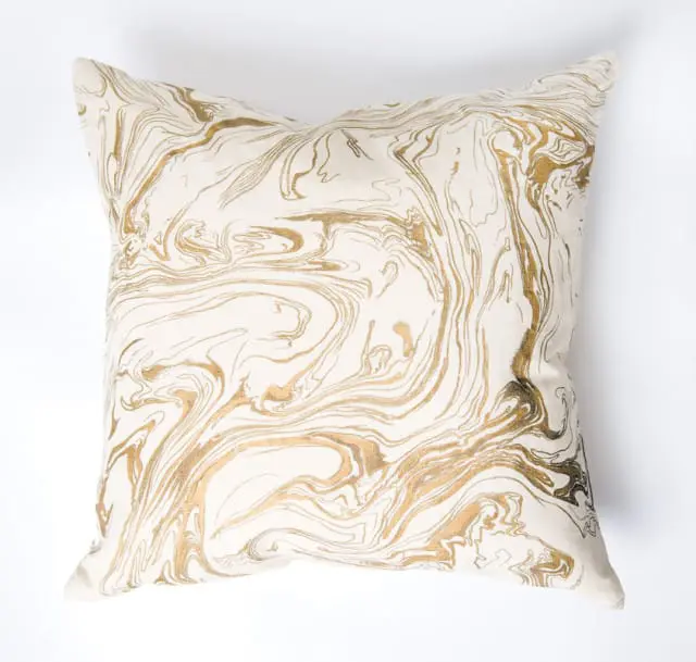 Cream pillow with a swirling gold marbled pattern