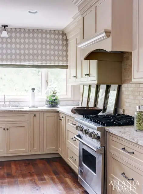 The kitchen was designed by Kathleen Rivers, whose cabinetry layout made the small, angled space feel larger, Amy Morris says, while neutral paint lightened up the room. The dark island anchored the space, with stools from Arteriors. Morris used hardware from Top Knobs, fixtures from Circa Lighting and assorted window treatments, art and decorative objects. The kitchen extended to the porch, where iron chairs and a cast-concrete table designed to withstand the elements contrasted with the wood.