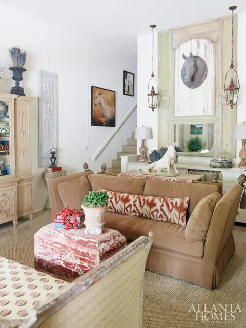 Soaring ceilings and the room's near-symmetrical simplicity served as the launching point for antiques dealer Sally Johannessen, who brought key pieces, such as a large French boiserie, to the guest house. A French pastry table was the perfect solution to divide the narrow space between a living area and a functioning kitchen, and it served as a sofa back and prep area in one. She created a gathering place for guests to congregate at the beginning and end of their day to discuss their plans and discoveries, even imagining items they found on local hikes and placing them into the painted bookcase. For a high-low focus, pieces came from area thrift stores to flea markets in France, including finds such as 19th-century French zinc butcher's shop horse head and hanging lanterns. The pair of stag leg tables are reproductions by Bliss. A daybed also made an appearance in this room-she used a pair of twin headboards for a long, low look. She adds: "I am always happiest when I can find a creative use for something that needs to be rescued."
