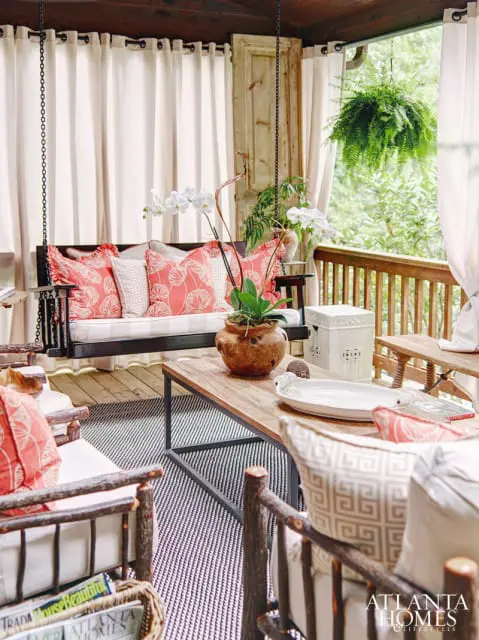 For a dramatic touch, Ann Sherrill, owner of the Cashiers-based home furnishings boutqique Rusticks, employed glossy black paint on a picnic-style dining table and porch swing, both of which were made by a local craftsman, and repeated that color in the rugs underfoot. The coral hue in the fabrics tied together the dining area and sitting area, which she deliberately seperated into two distinct spaces in the outdoor space.