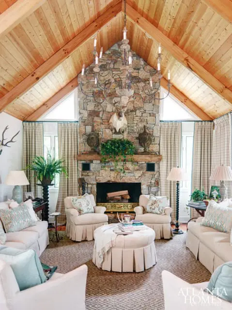 "Total comfort and charm was important to me in creating this space," says designer Francie Hargrove, who imbued this joint kitchen/living space with her signature touch of rustic elegance. Tailored draperies in French General Plaid, pillows covered in Cowtan & Tout's Rhododendron Linen and pleated skirts add a feminine touch-and soften the soaring ceiling and stone mantel.