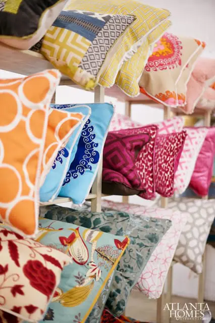 Assortment of decorative throw pillows in various patterns and colors, including orange with white circles, blue with white swirls, yellow geometric, and floral designs.