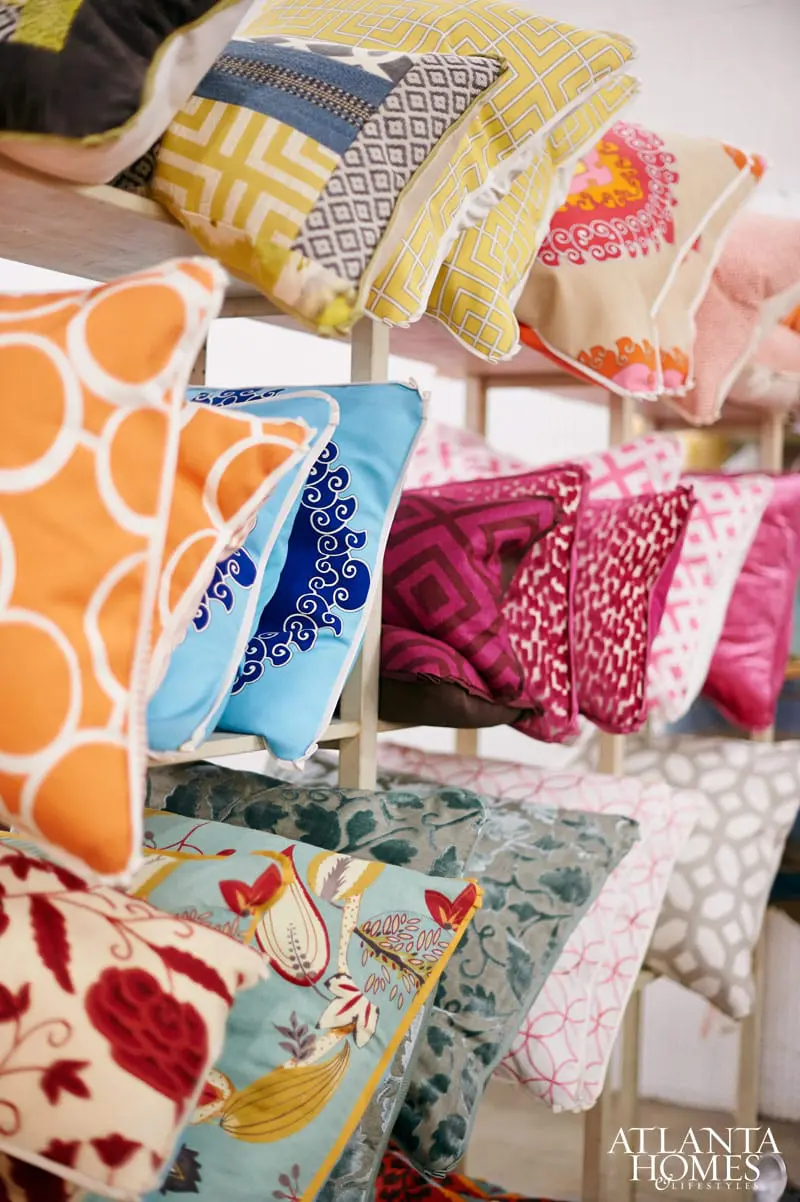 Assortment of decorative throw pillows in various patterns and colors, including orange with white circles, blue with white swirls, yellow geometric, and floral designs.