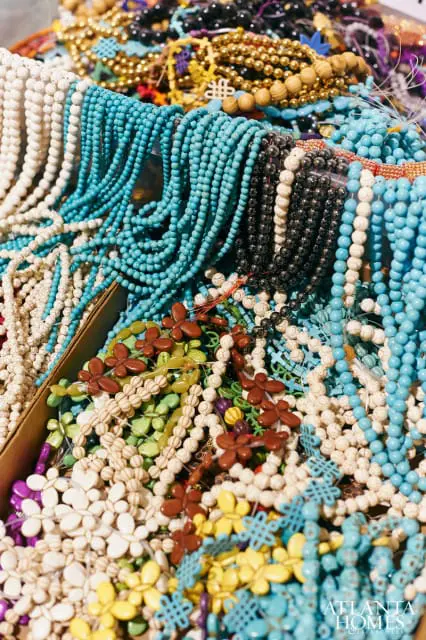 Close-up of a variety of colorful beaded necklaces and bracelets, including turquoise, white, black, gold, and floral-shaped beads.