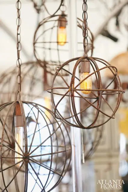 Close-up of rustic, spherical metal cage pendant lights with Edison bulbs hanging from chains.