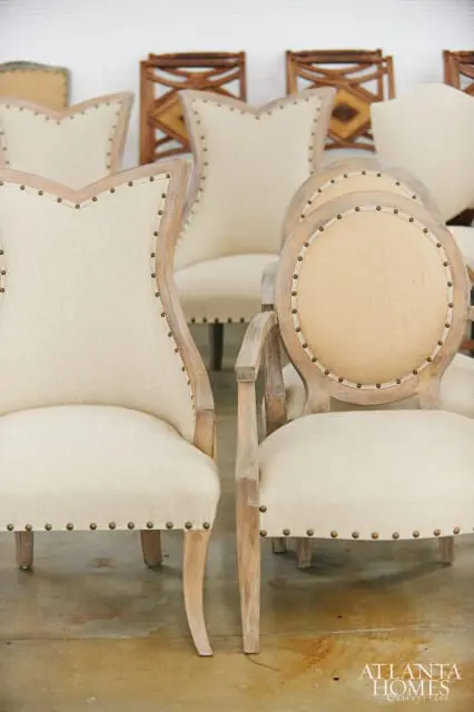Upholstered chairs with light-colored fabric and nailhead trim, featuring light wood frames and curved legs.